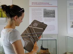A museum visitor playing with the "bandolo" Besucher_Recycling