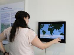 A museum visitor is trying out the interactive touchscreen Besucher_Migration